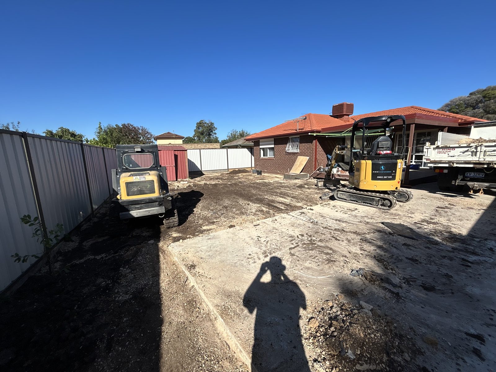Branded Rigid Earthworks excavator and Posi-Track levelling a cleared residential yard in St Albans
